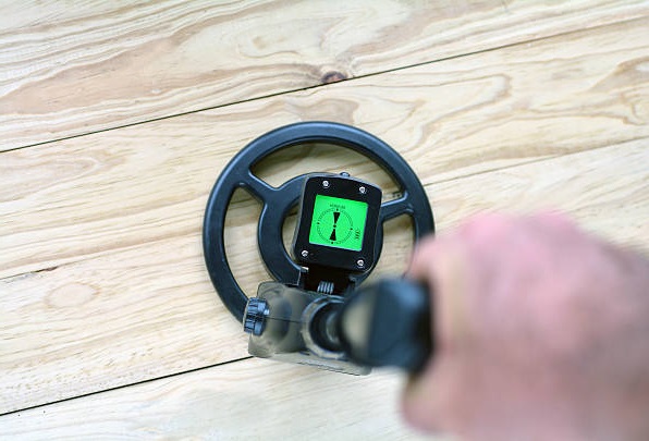 man using a metal detector on a wood surface